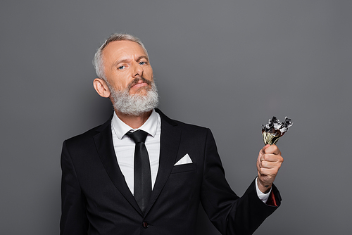 bearded middle aged businessman holding burning dollar banknotes isolated on grey