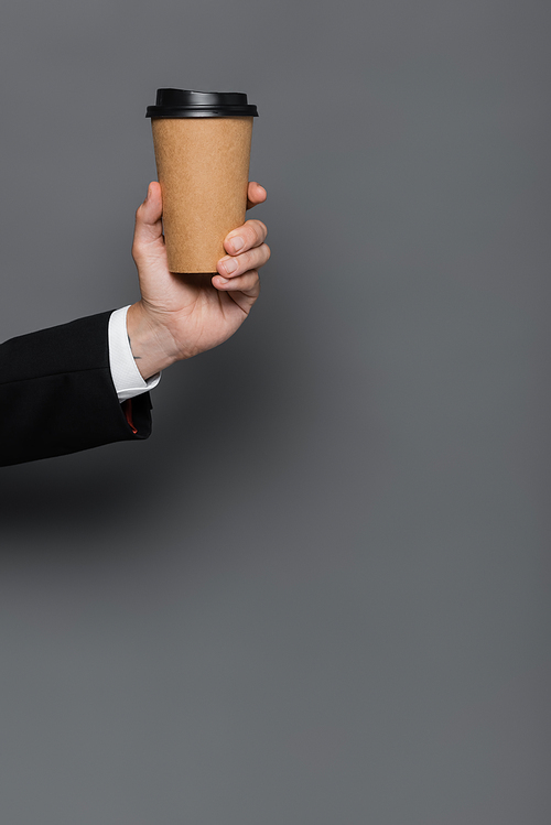 cropped view of businessman holding paper cup on grey