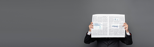 middle aged businessman obscuring face with newspaper on grey, banner