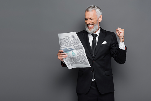 happy middle aged businessman reading newspaper on grey