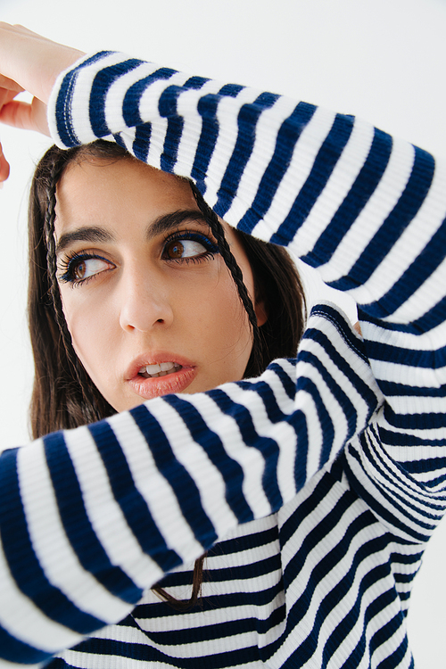 trendy armenian woman in striped pullover looking away isolated on white