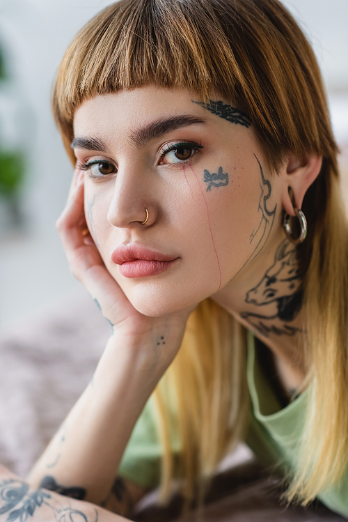 close up view of pretty woman with tattoo and piercing  at home