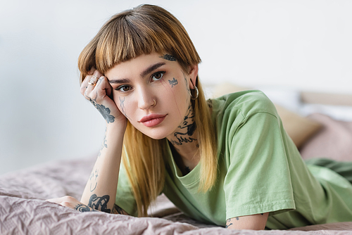 young tattooed woman  while lying on bed
