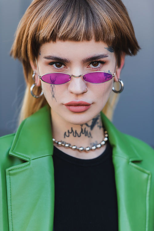 stylish tattooed woman in eyeglasses  outdoors