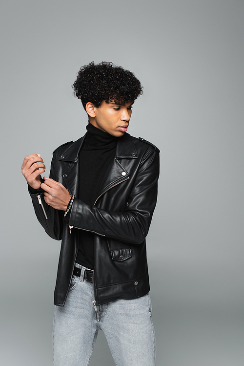 african american man in trendy leather jacket posing isolated on grey