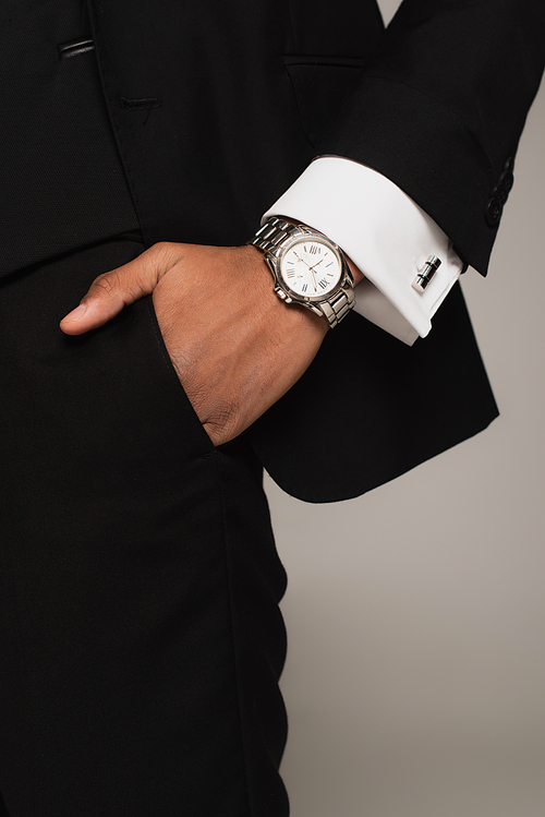 cropped view of african american man in black formal wear and wristwatch holding hand in pocket isolated on grey