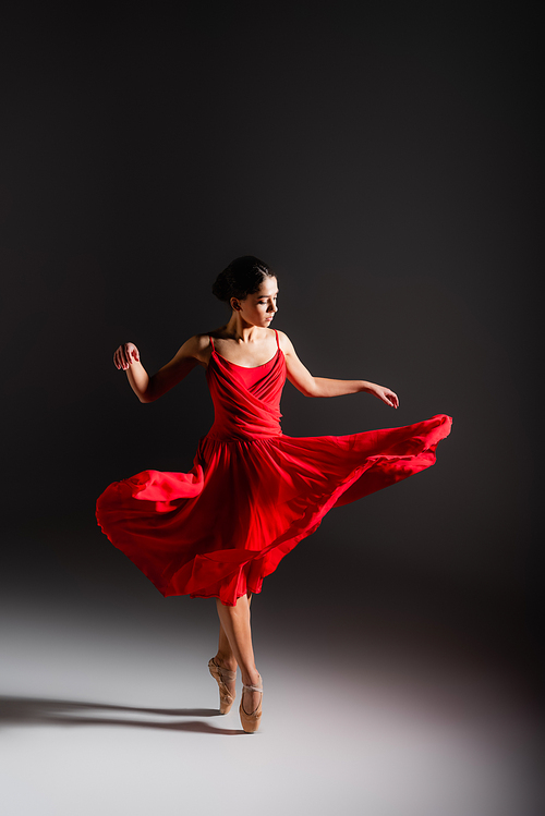 Ballerina in dress spinning on black background