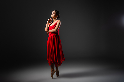 Ballerina in pointe shoes standing on black background