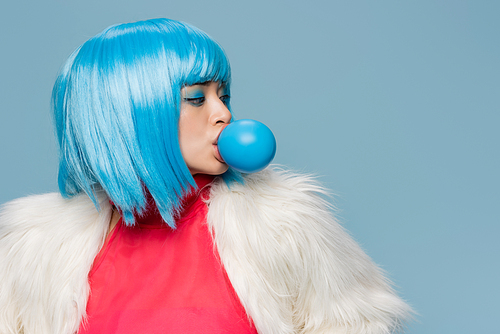 Fashionable asian woman blowing bubble gum isolated on blue