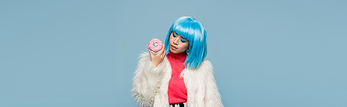 Trendy asian woman holding donut isolated on blue, banner