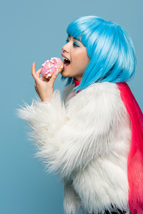 Young asian pop art woman holding delicious donut near open mouth isolated on blue