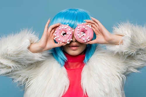 Stylish woman in bright wig holding donuts near face isolated on blue