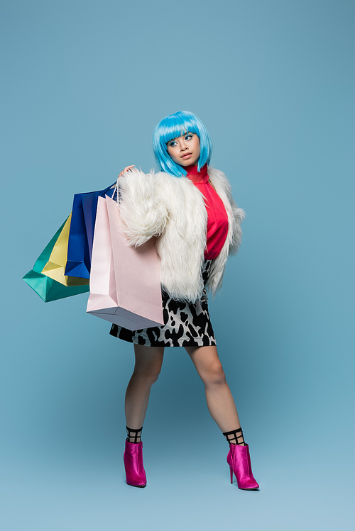 Asian pop art woman holding shopping bags and looking away on blue background