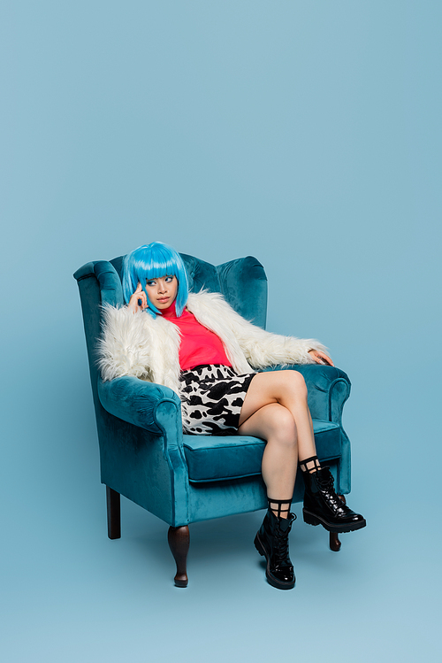 Asian woman in pop art style sitting on armchair on blue background