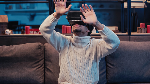 african american man in virtual reality headset gesturing at home