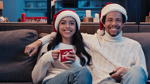 cheerful african american couple watching movie on christmas