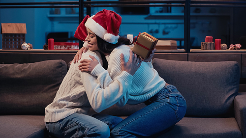 cheerful happy african american woman holding christmas present and hugging boyfriend