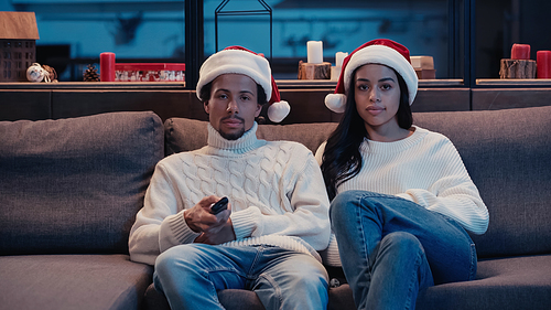 African american man and woman in santa hats watching movie