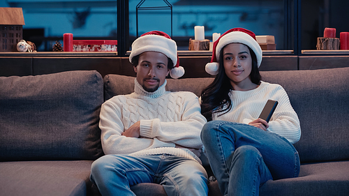 African american couple in santa hats watching movie