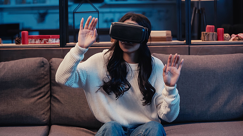 african american woman in virtual reality headset gesturing while gaming at home