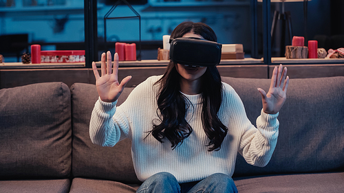 african american woman in virtual reality headset gesturing at home
