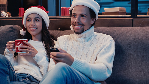 happy african american man and woman watching movie on christmas