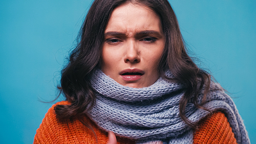 sick woman in warm scarf suffering from pain in sore throat isolated on blue