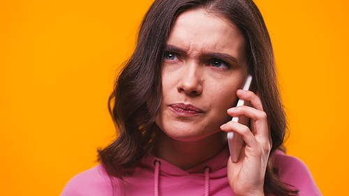 worried woman talking on mobile phone isolated on yellow