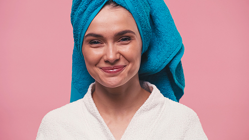 young woman with perfect skin and towel on head smiling at camera isolated on pink