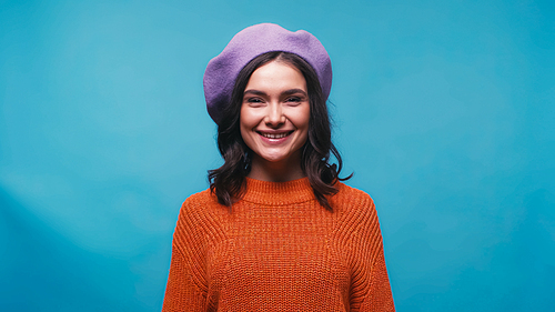 joyful woman in orange sweater and purple beret  isolated on blue
