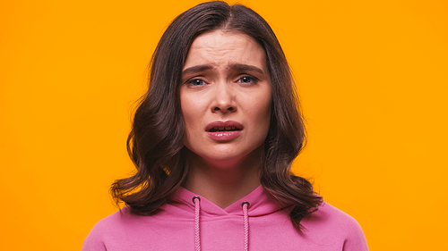 upset woman in pink hoodie  isolated on yellow