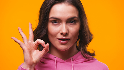 positive woman showing okay gesture while  isolated on yellow