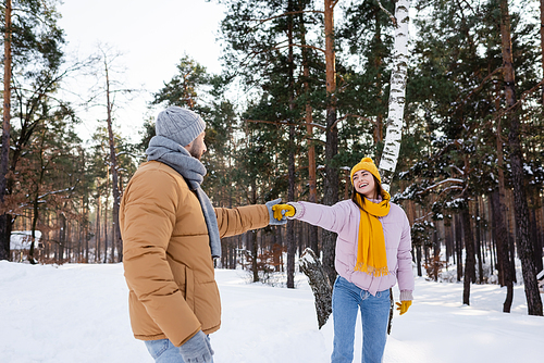 Smiling woman holding hand of boyfriend in winter park
