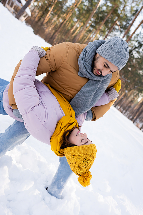 Young man having fun with girlfriend in winter outfit outdoors
