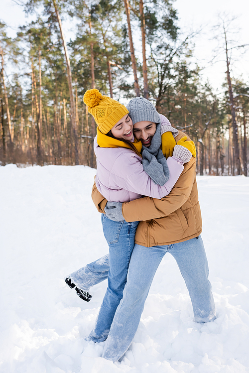 Cheerful couple embracing in snowy park