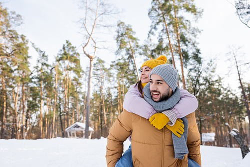 Smiling woman piggybacking on boyfriend in winter park