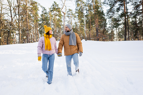 Young couple holding hands while walking on snow