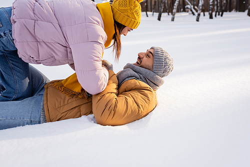 Side view of cheerful couple playing on snow in park