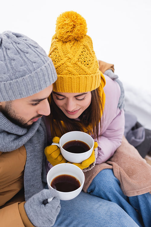 High angle view of couple in winter outfit holding coffee cups in snowy park
