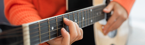 cropped view of young woman playing acoustic guitar at home, banner