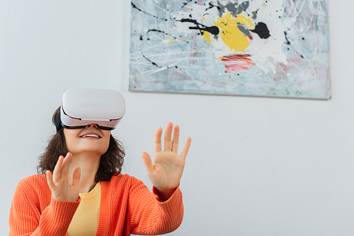 young happy woman in vr headset gesturing during simulation game at home
