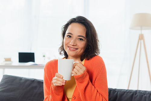 happy young woman holding mug at home
