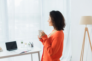 side view of pleased young woman holding mug at home