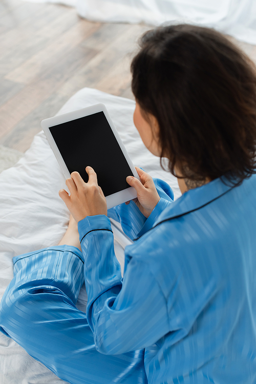 high angle view of blurred young woman in blue pajamas using digital tablet with blank screen