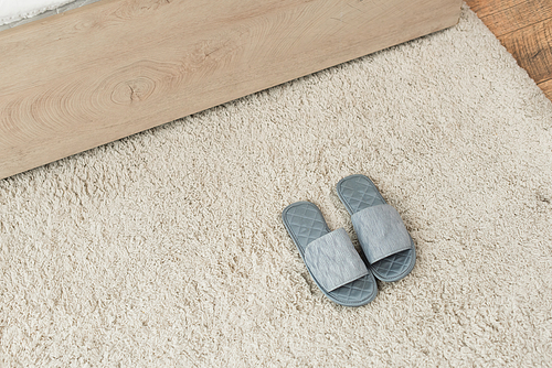 high angle view of grey slippers on beige carpet