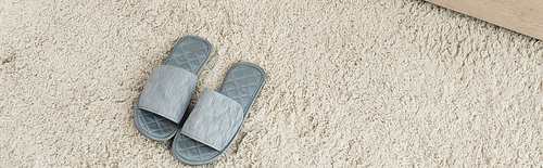 high angle view of grey slippers on beige carpet, banner