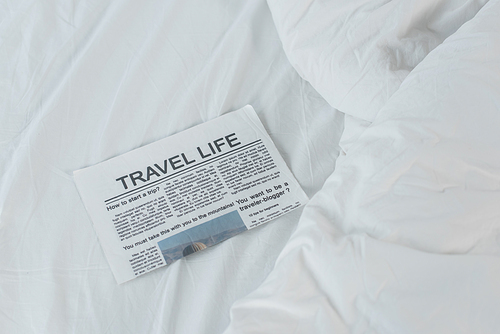 high angle view of travel life newspaper on white bed