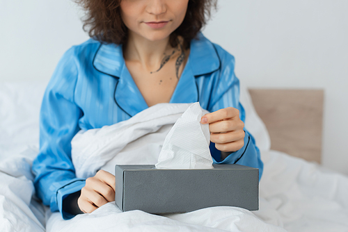 cropped view of tattooed woman reaching napkin in tissue box