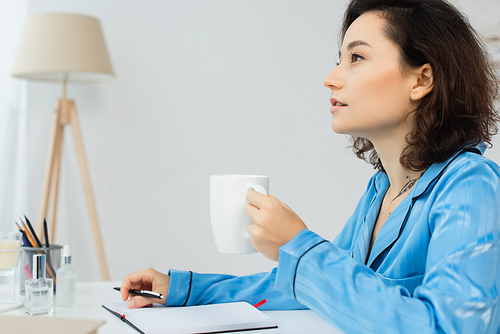 pensive woman holding cup of coffee and thinking at home
