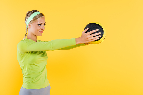 happy woman in green long sleeve t-shirt training with ball isolated on yellow
